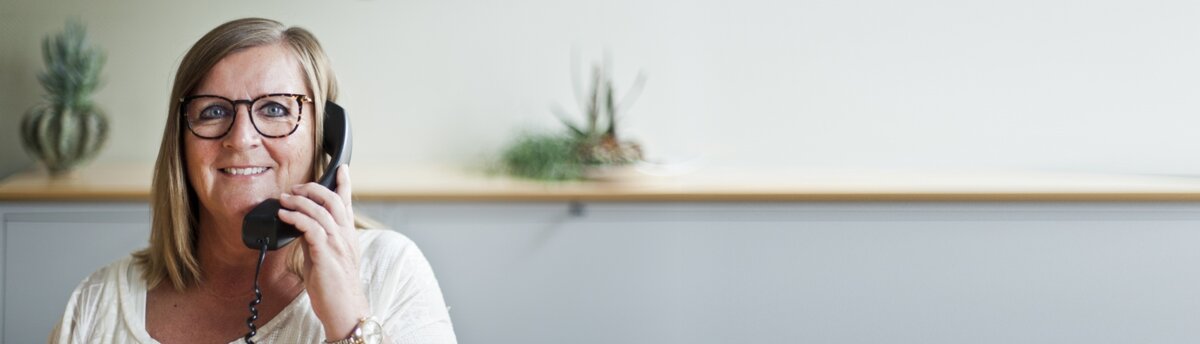 Tandlæge Bente Canter's receptionist; Tina Andersen smiler mens hun taler i telefon